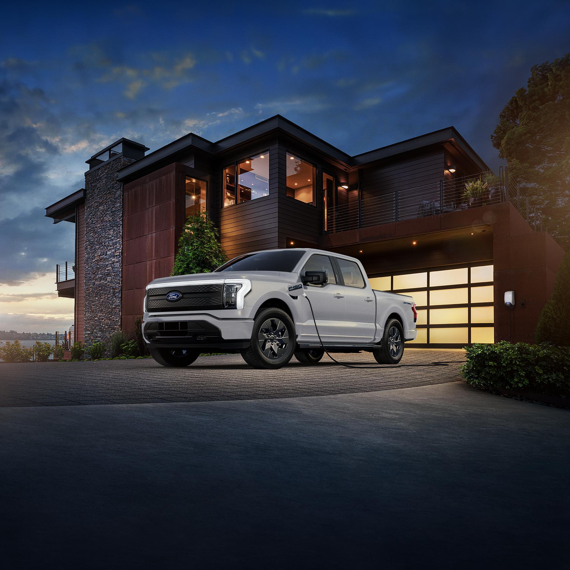 Ford F-150® Lightning® truck being charged in the driveway of a modern luxury home