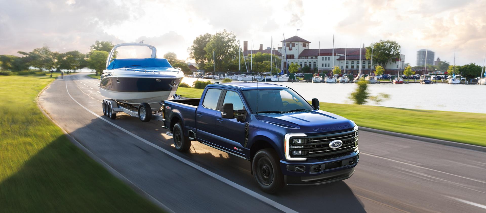 2026 Ford Super Duty® F-350® Platinum® model in Argon Blue towing a speed boat on a paved road
