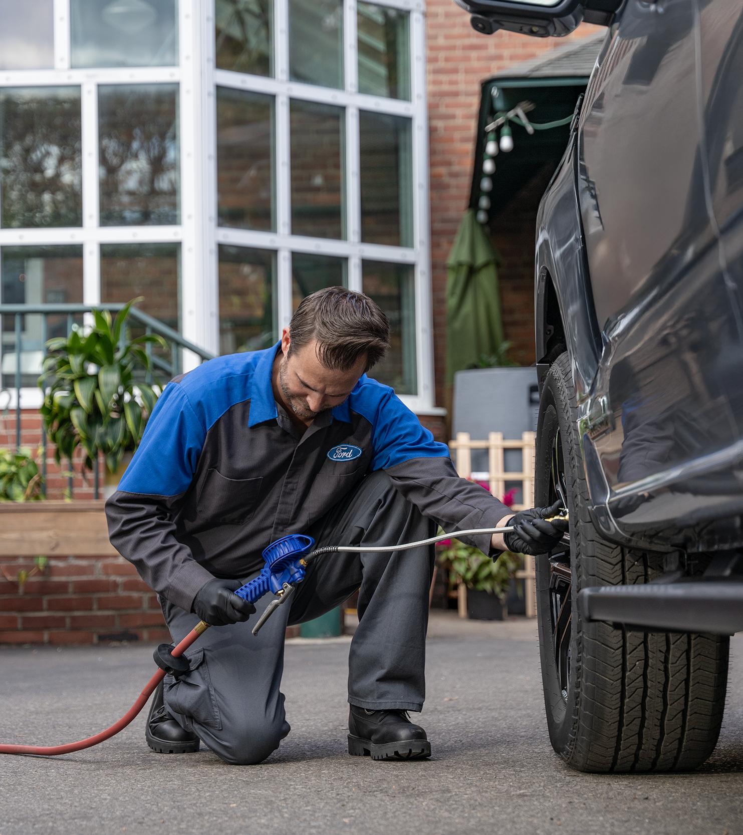 A Ford Mobile Service technician fills air into a tire