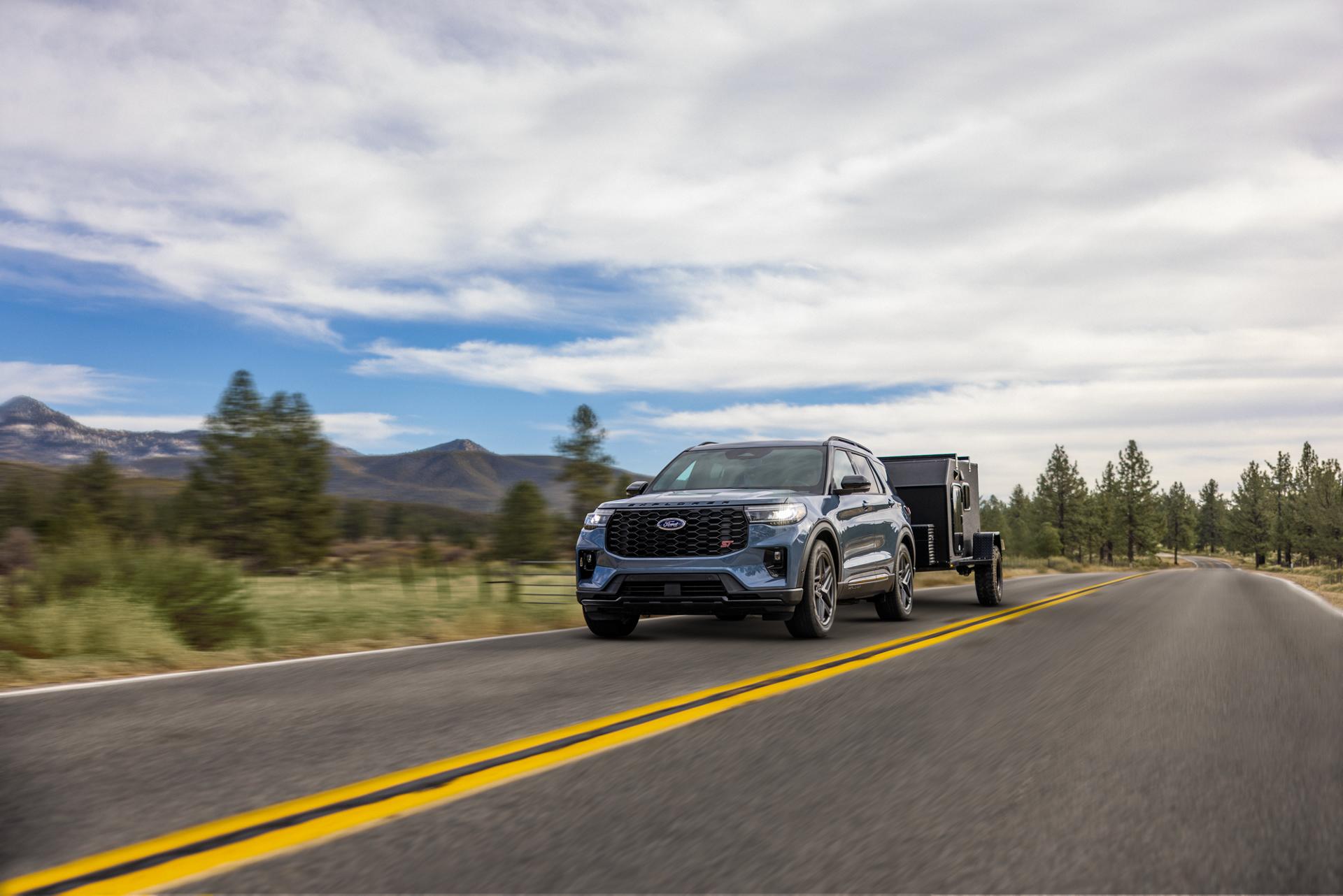 A 2026 Ford Explorer® SUV pulling a trailer on a highway through the mountains