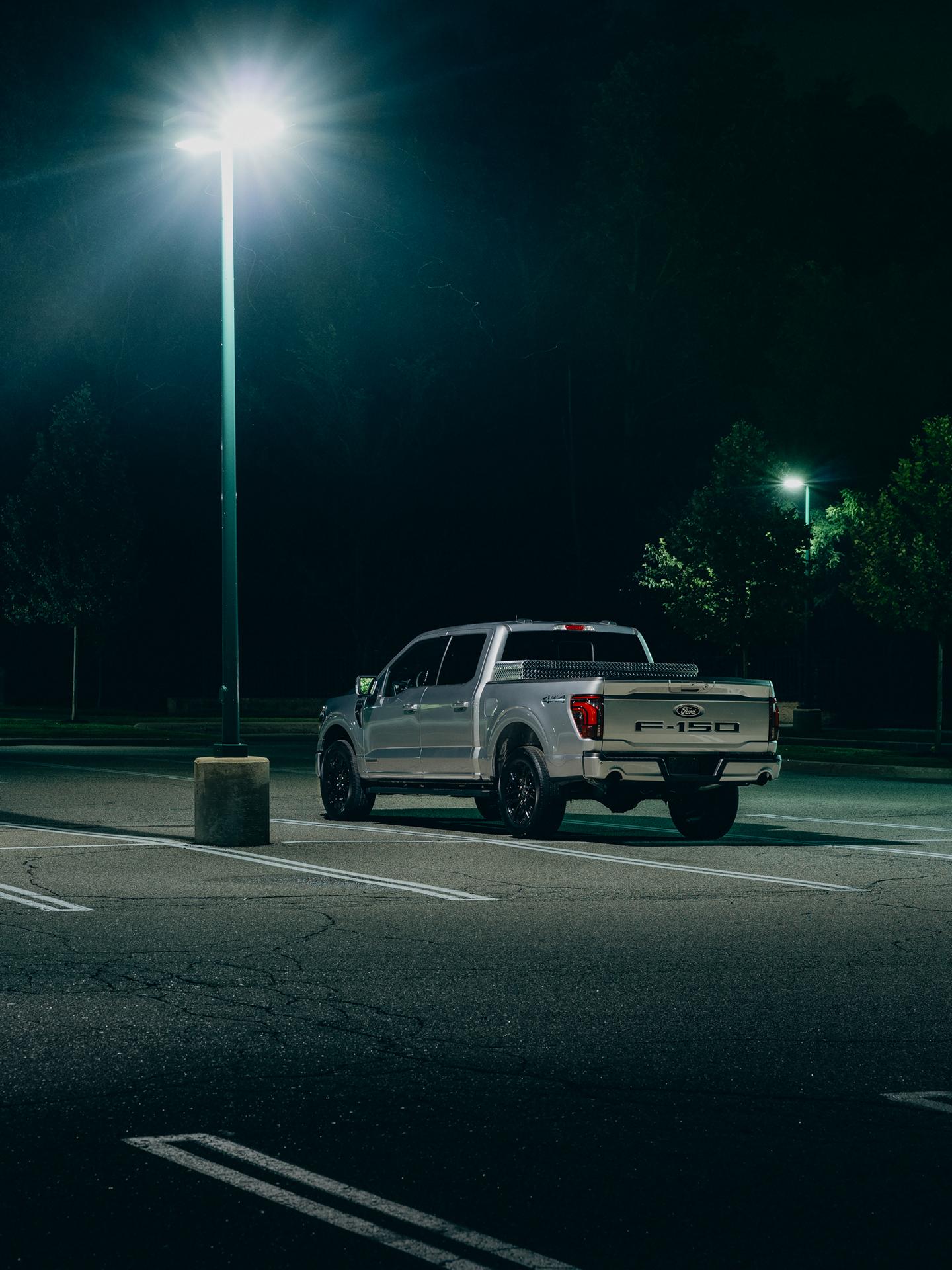 A Ford F-150® truck is parked in an empty lot under a street light at night