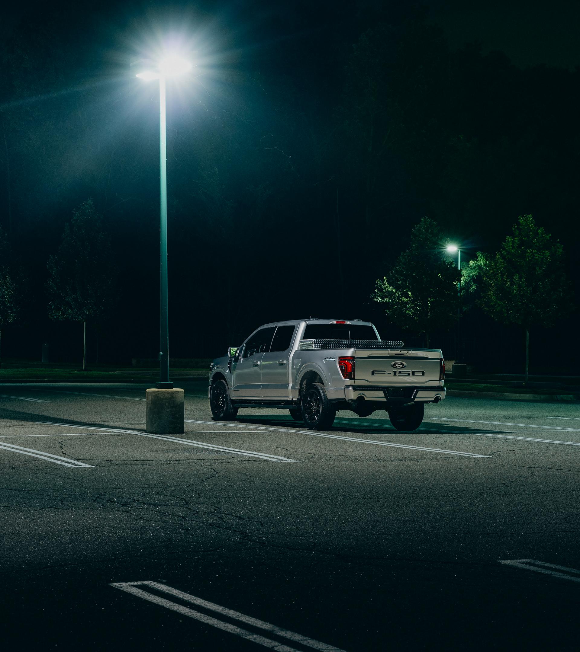 A Ford F-150® truck is parked in an empty lot under a street light at night