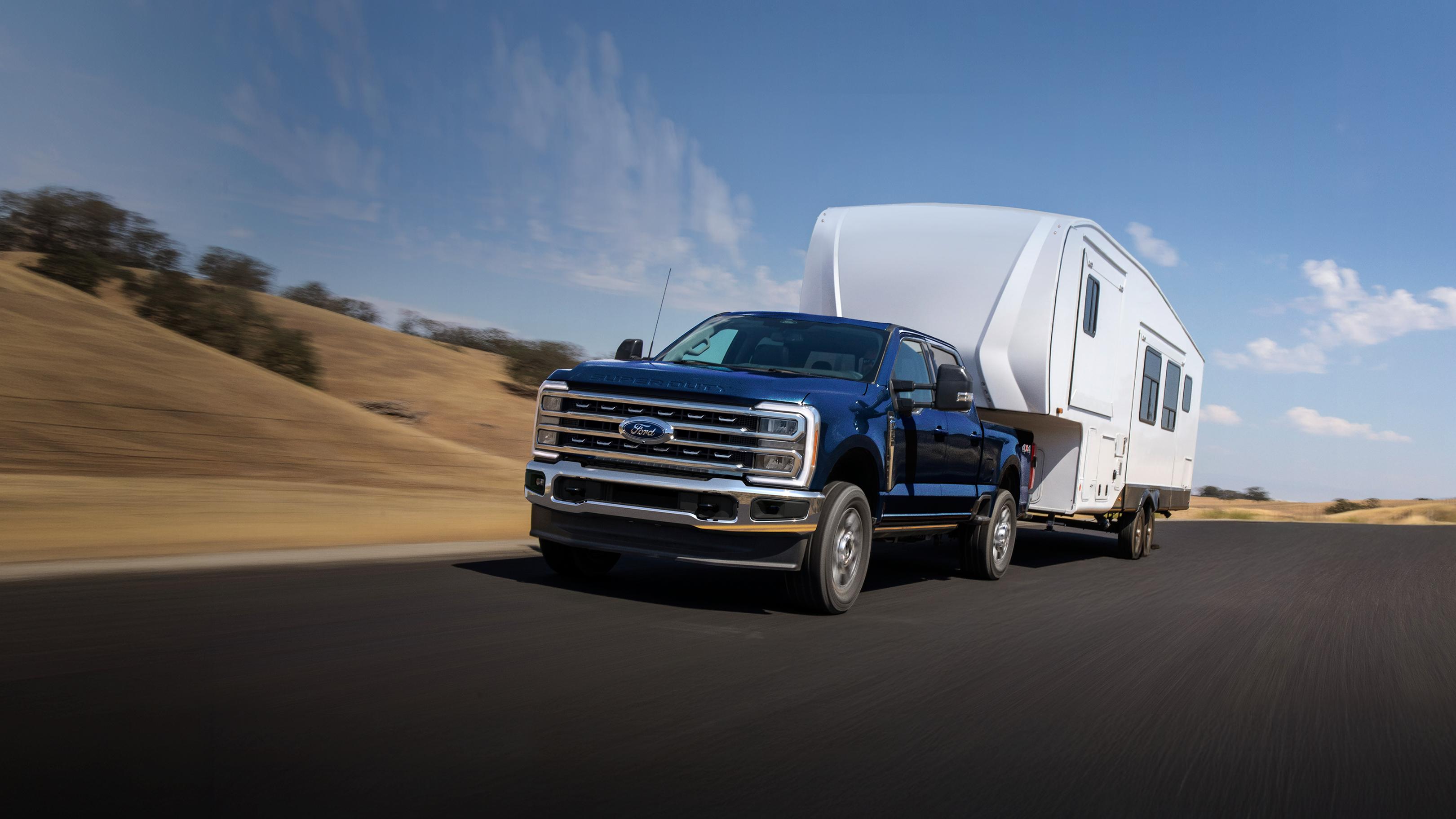 2025 Ford Super Duty® F-250® Lariat® model in Antimatter Blue pulling a large camper on a paved road