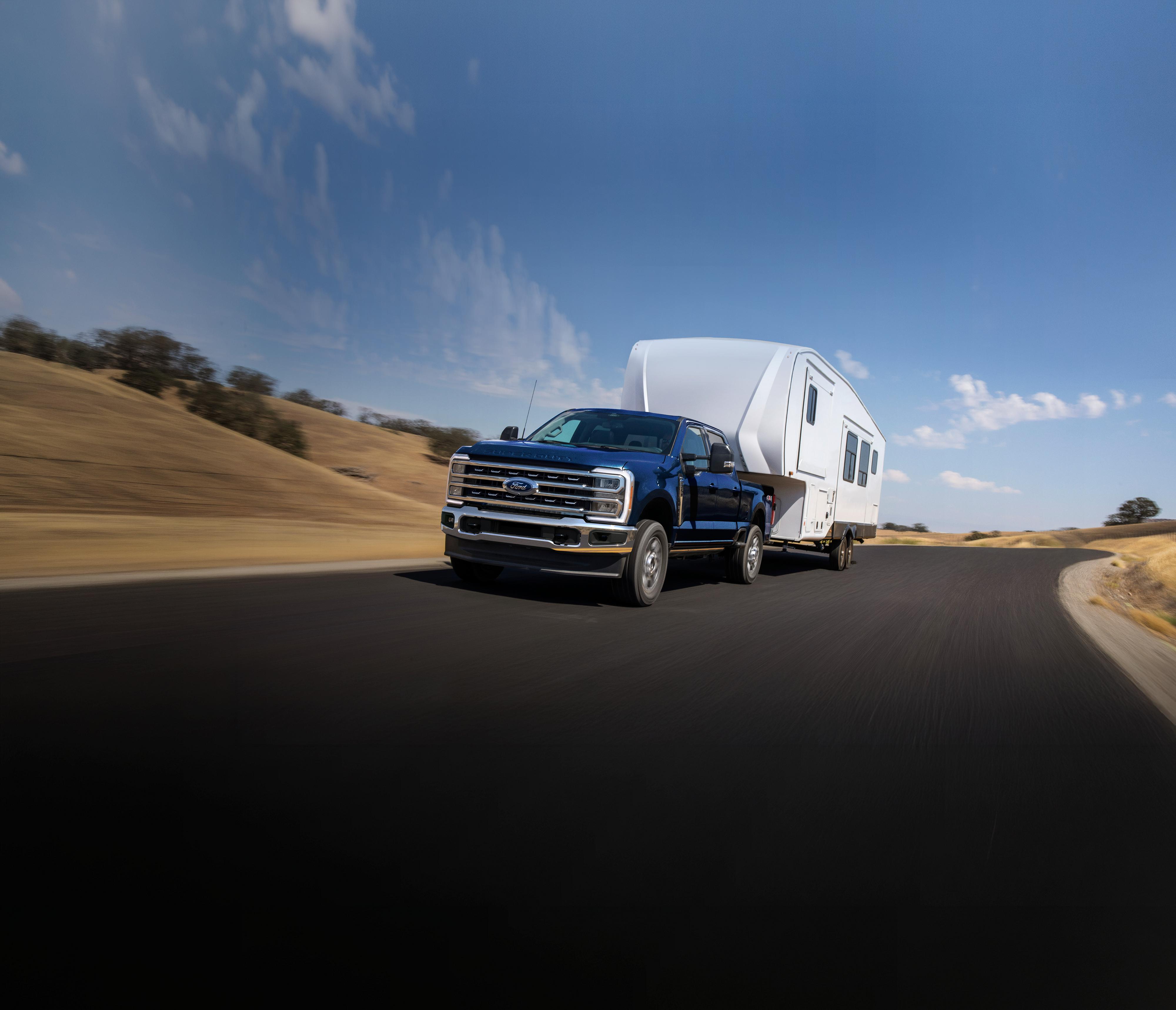 2025 Ford Super Duty® F-250® Lariat® model in Antimatter Blue pulling a large camper on a paved road