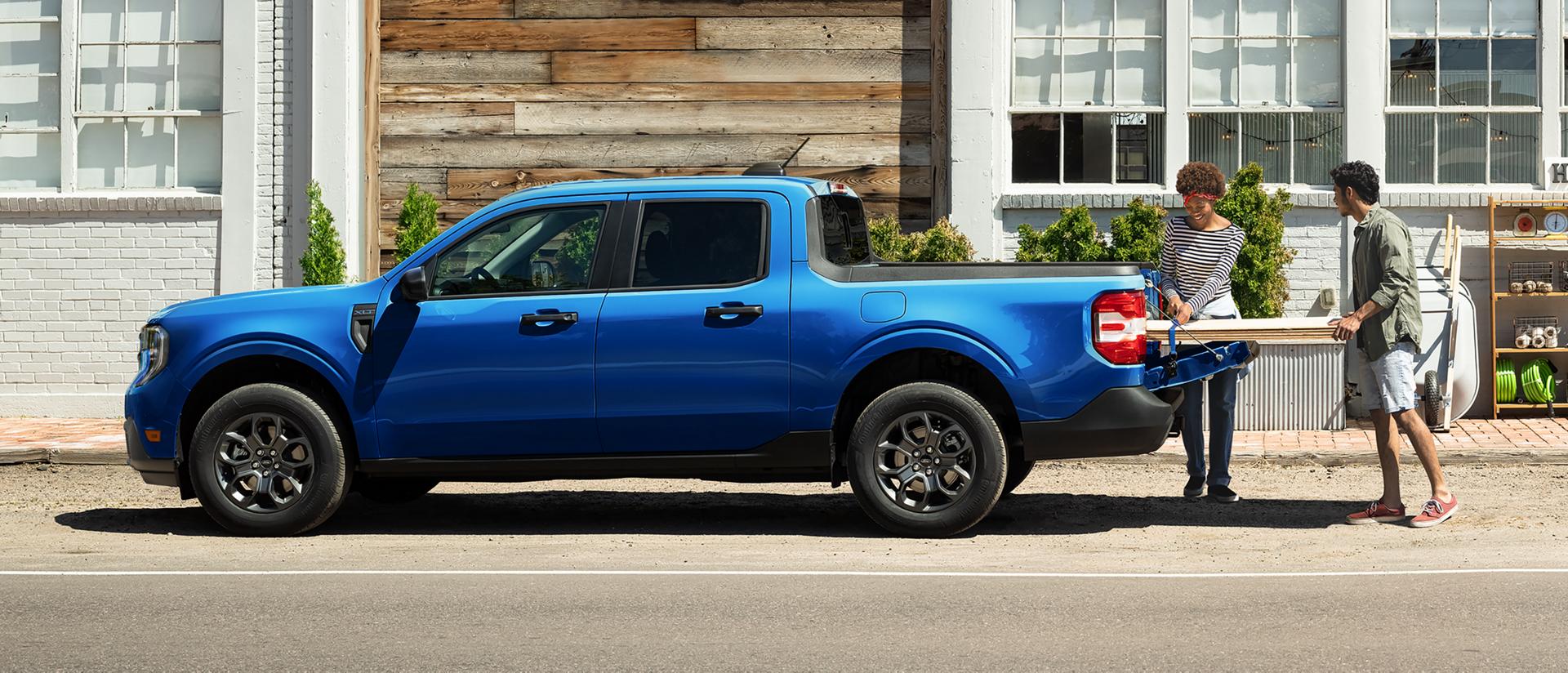 A couple load up lumber in the back of their Ford Maverick® pickup