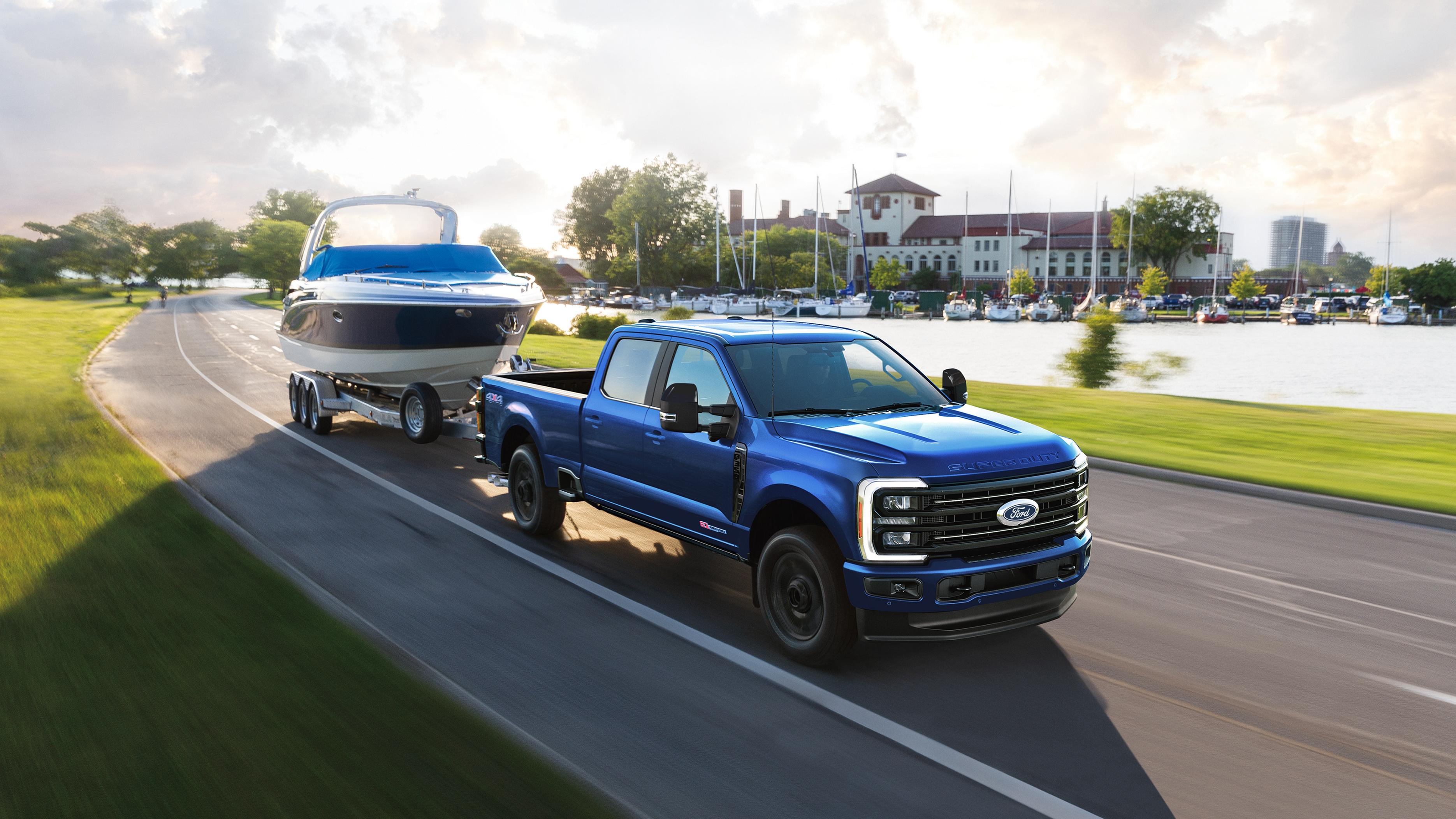 2027 Ford Super Duty® F-350® Platinum® model in Neptune Blue towing a speed boat on a paved road