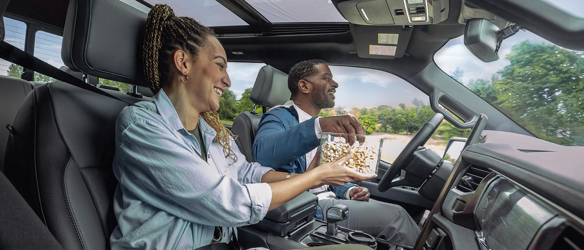 A driver and passenger eating popcorn in a 2025 Ford F-150® Lightning® pickup, with the BlueCruise feature operating