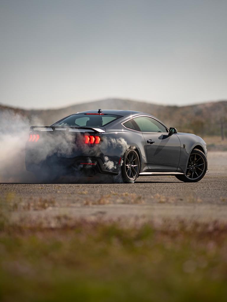 2025 Ford Mustang® Dark Horse™ coupe in Vapor Blue Metallic with a driver performing burnouts on a closed course