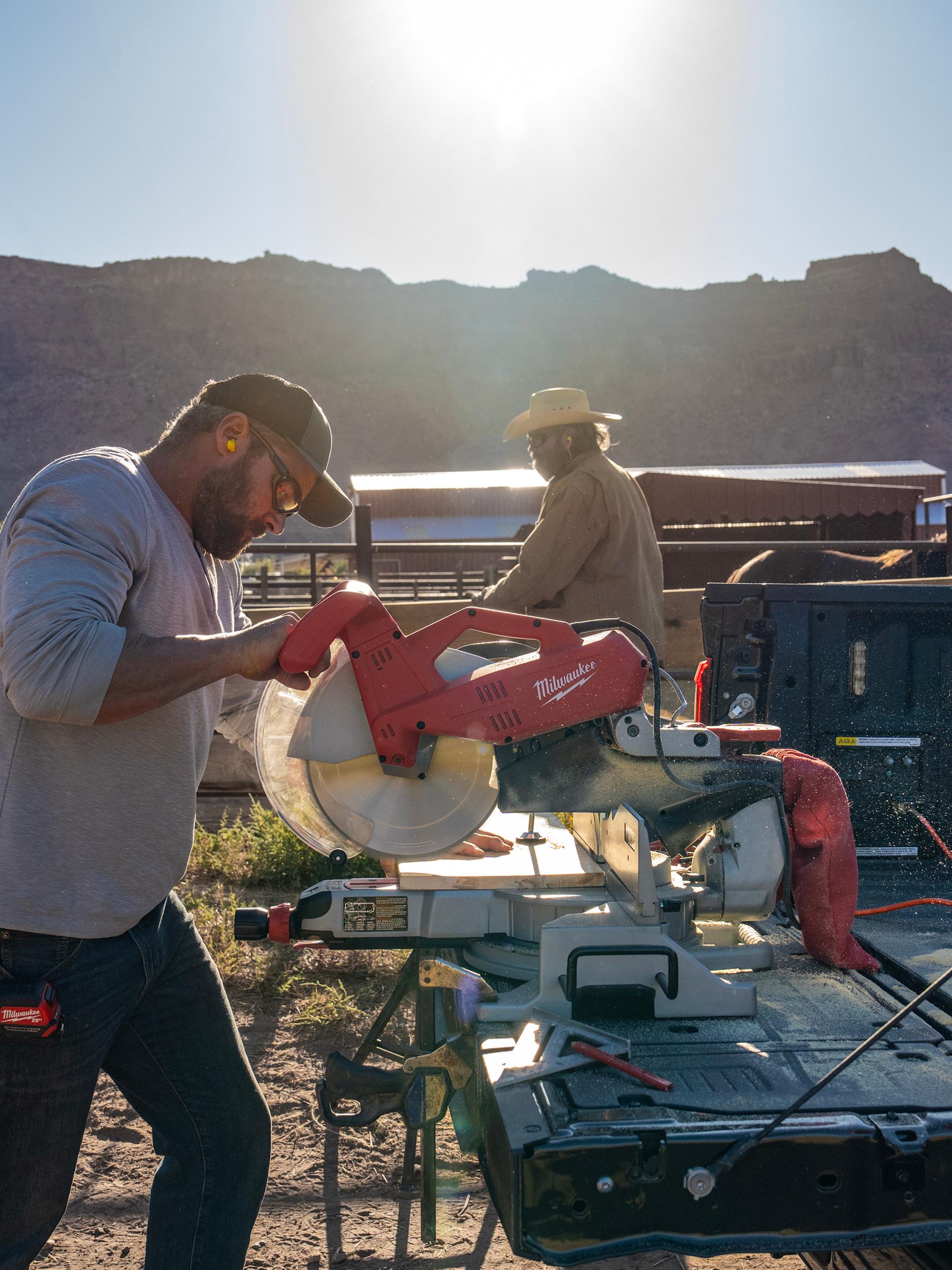 Man using a chop saw plugged into the Pro power Onboard™ feature on the tailgate of a 2027 Ford F-150® truck