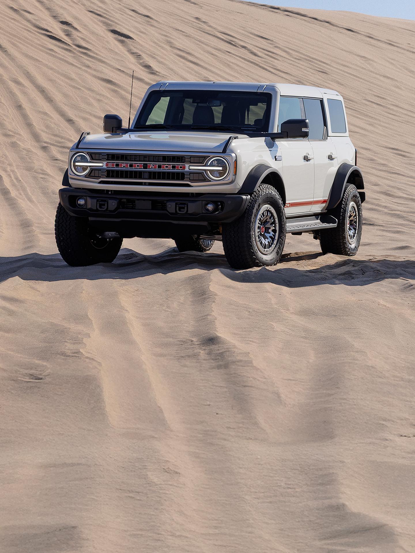 2026 Ford Bronco® SUV with the available 60th Anniversary Package parked on a sand dune on a sunny morning