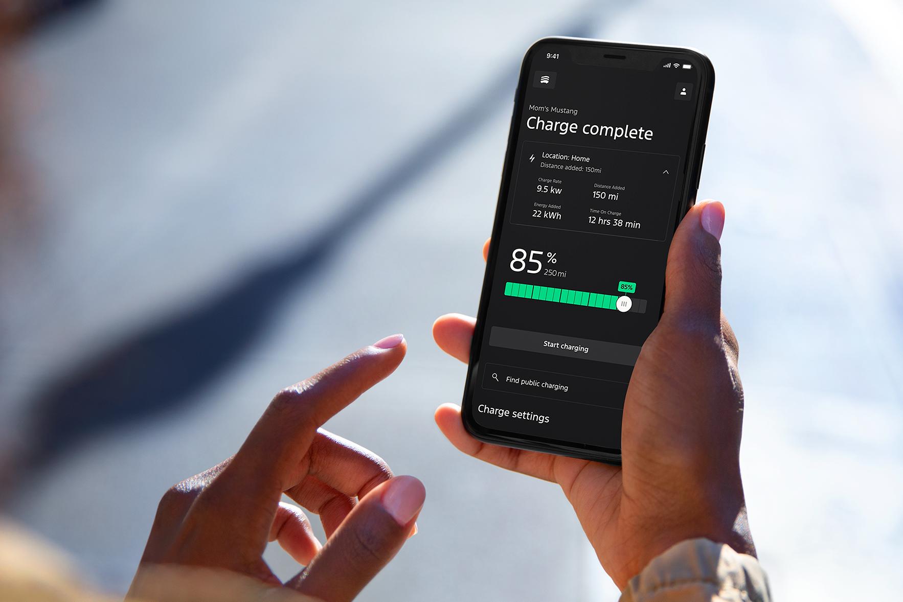 Person holding their smartphone while reviewing their vehicle charging level