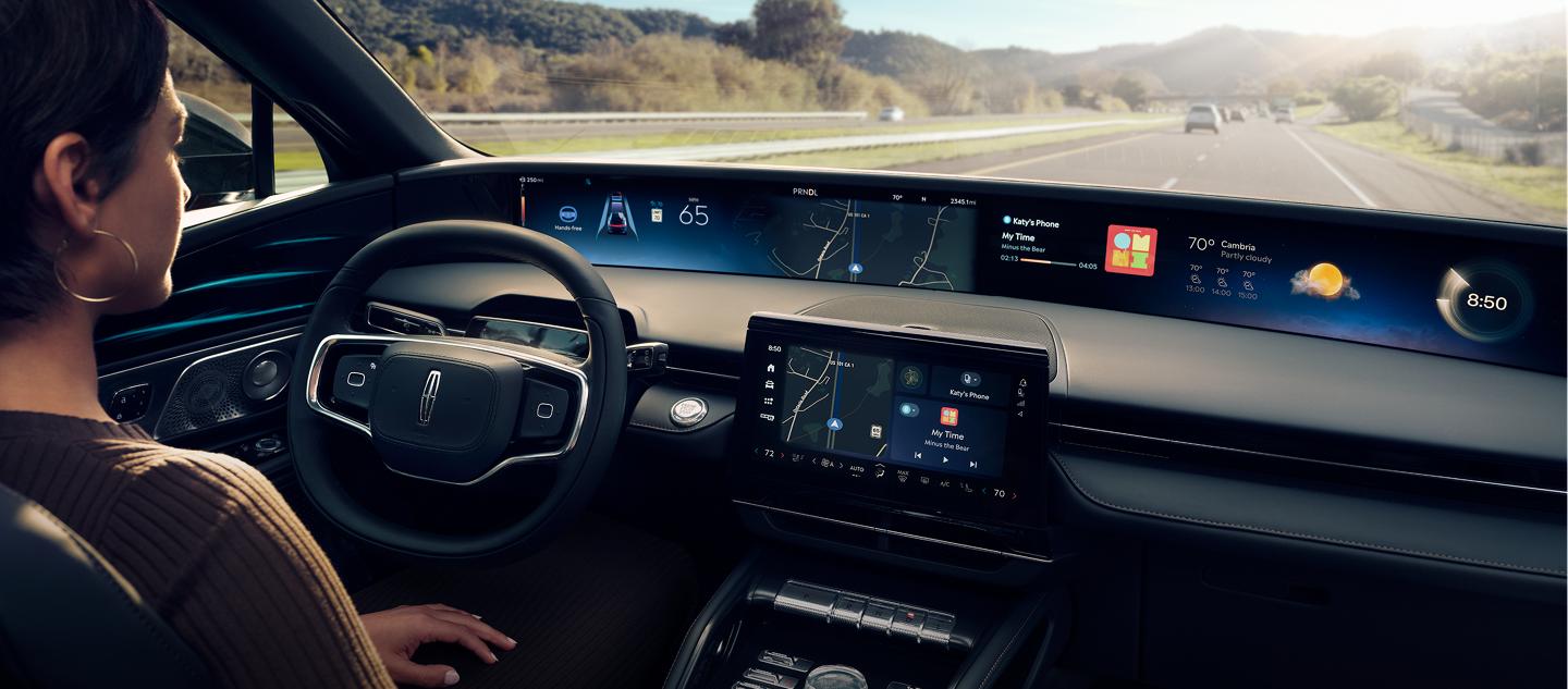 A woman is shown driving Lincoln Nautilus SUV hands-free using Lincoln BlueCruise on a highway.