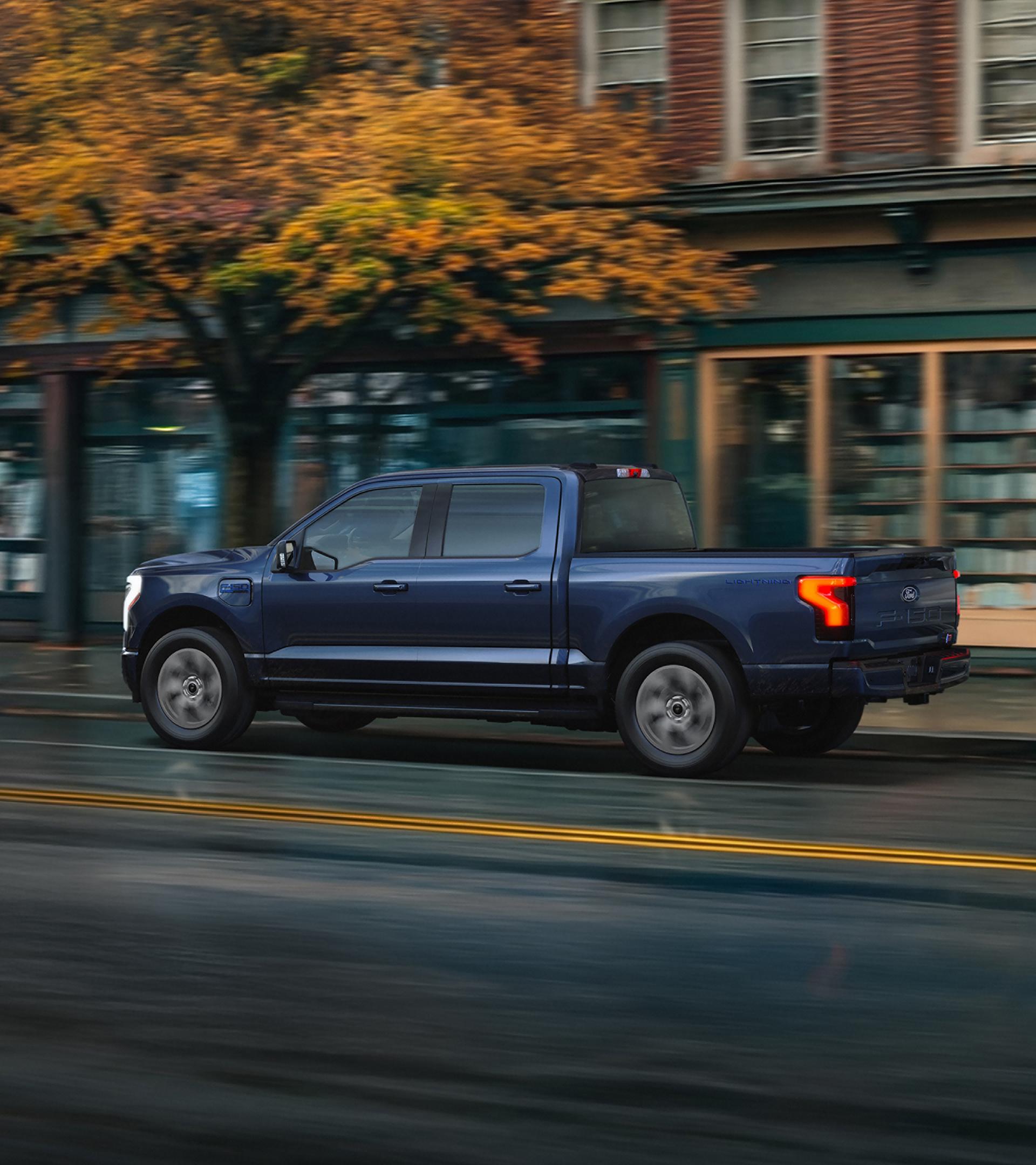 2025 Ford F-150 Lighting driving through city street in autumn